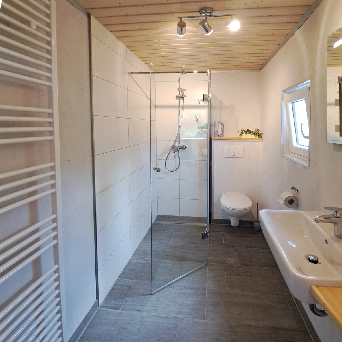 Schickes Bad mit Handtuchtrockner und großzügiger Dusche